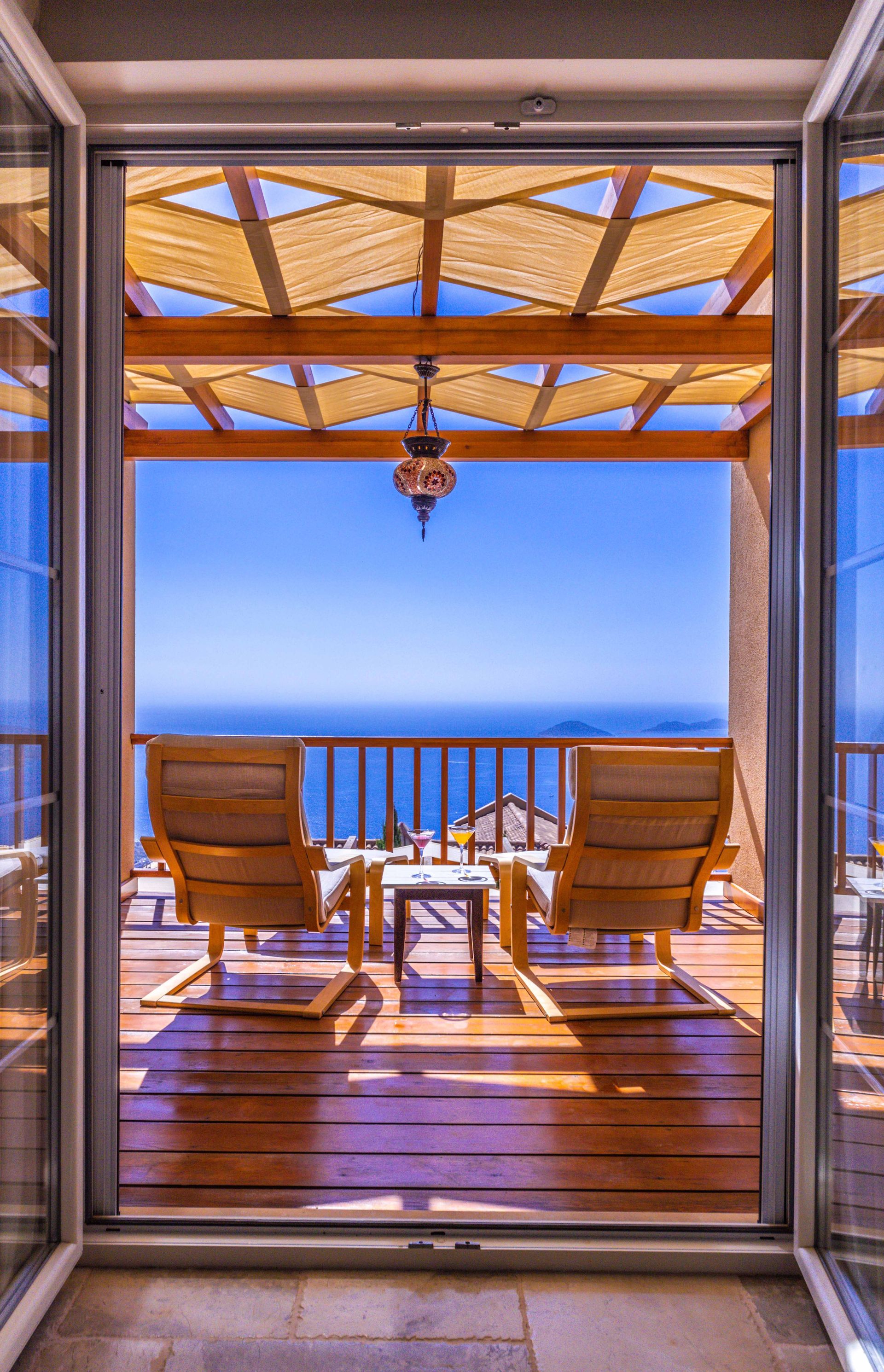 Relax on a seaside terrace with wooden chairs and breathtaking ocean views.